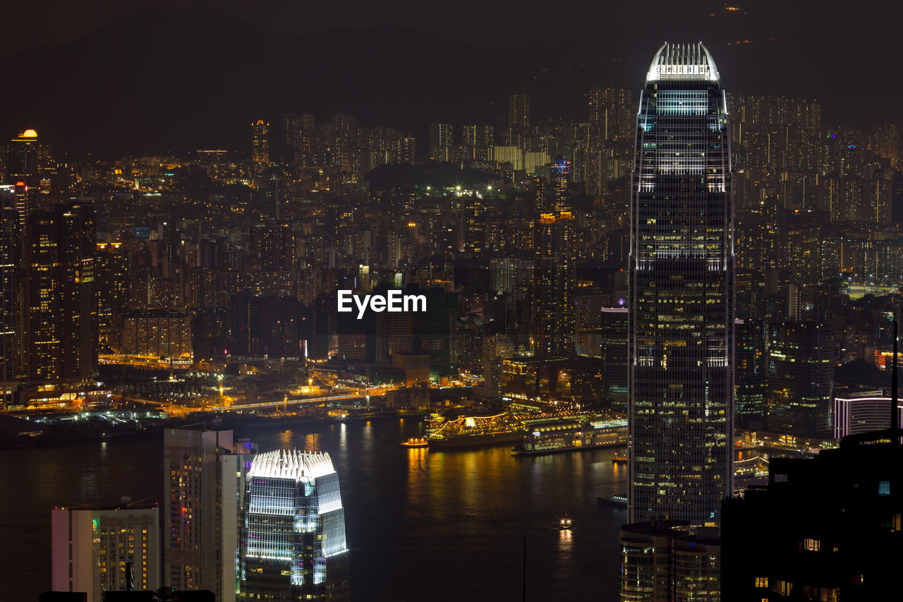 Buildings at victoria harbour in illuminated city at night