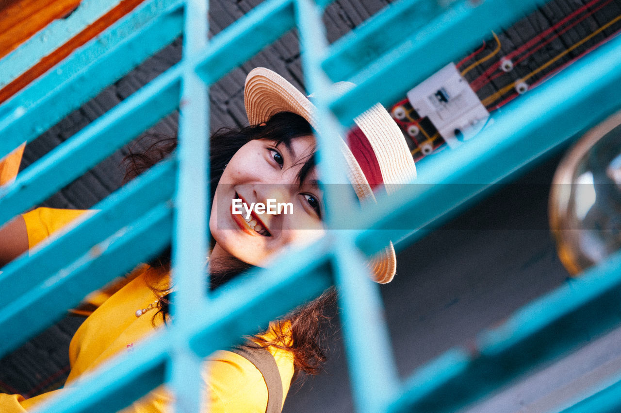 Portrait of smiling young woman seen through fence