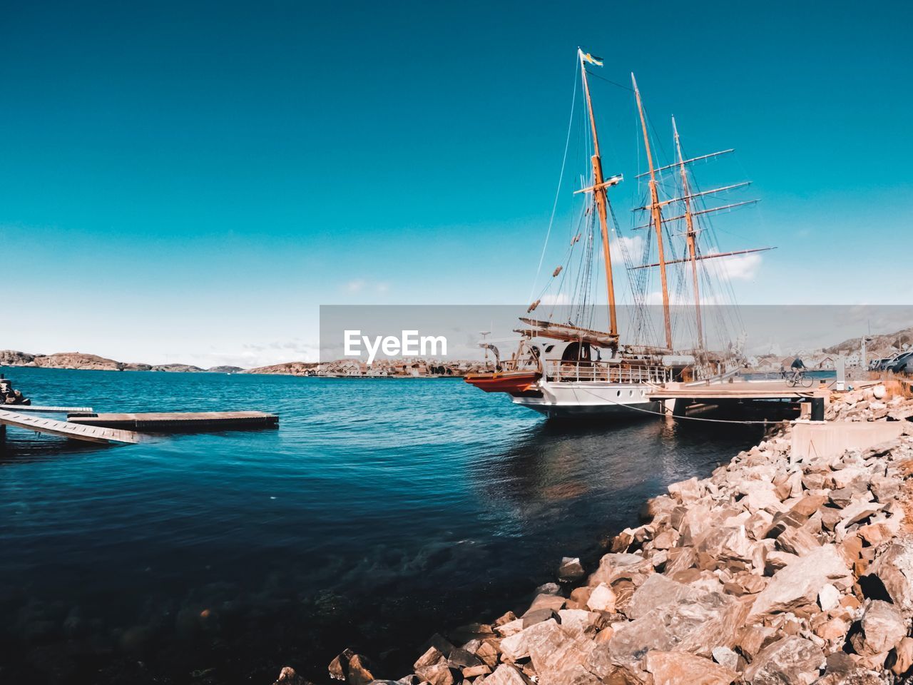 Sailboats moored on sea against blue sky