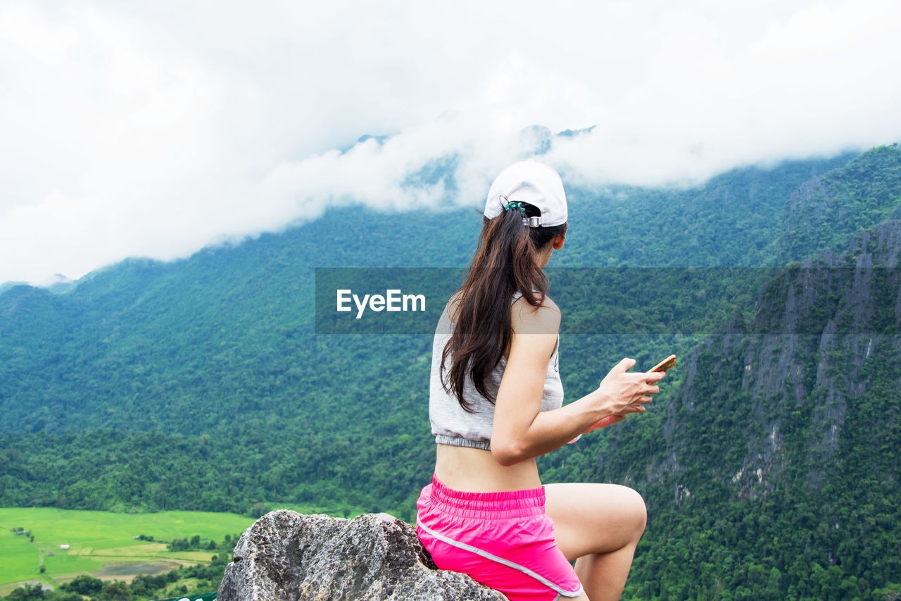 Young woman using mobile phone against mountain