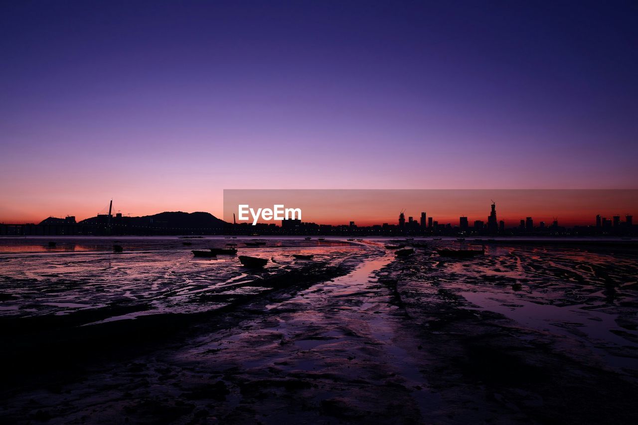 Silhouette of sea and cityscape during sunset