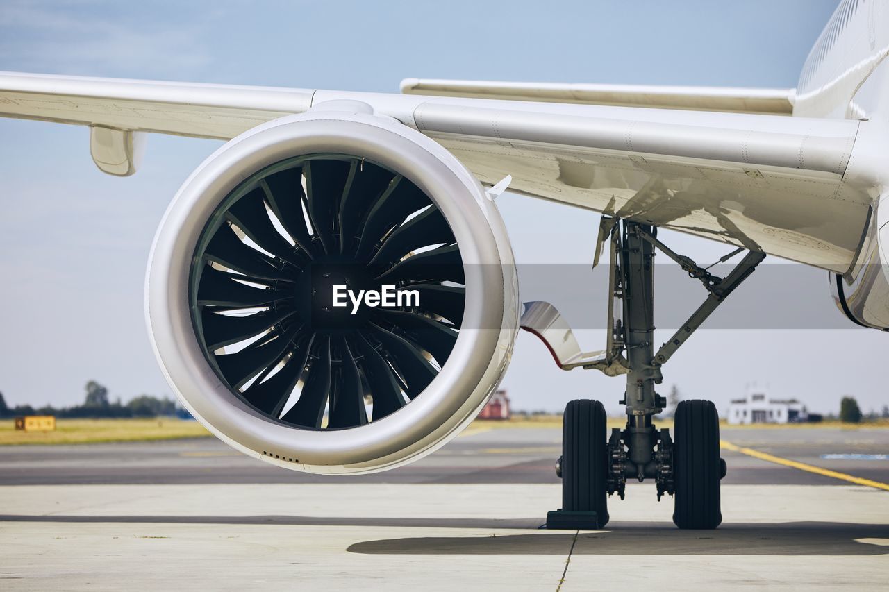 Close-up of airplane on airport runway against sky