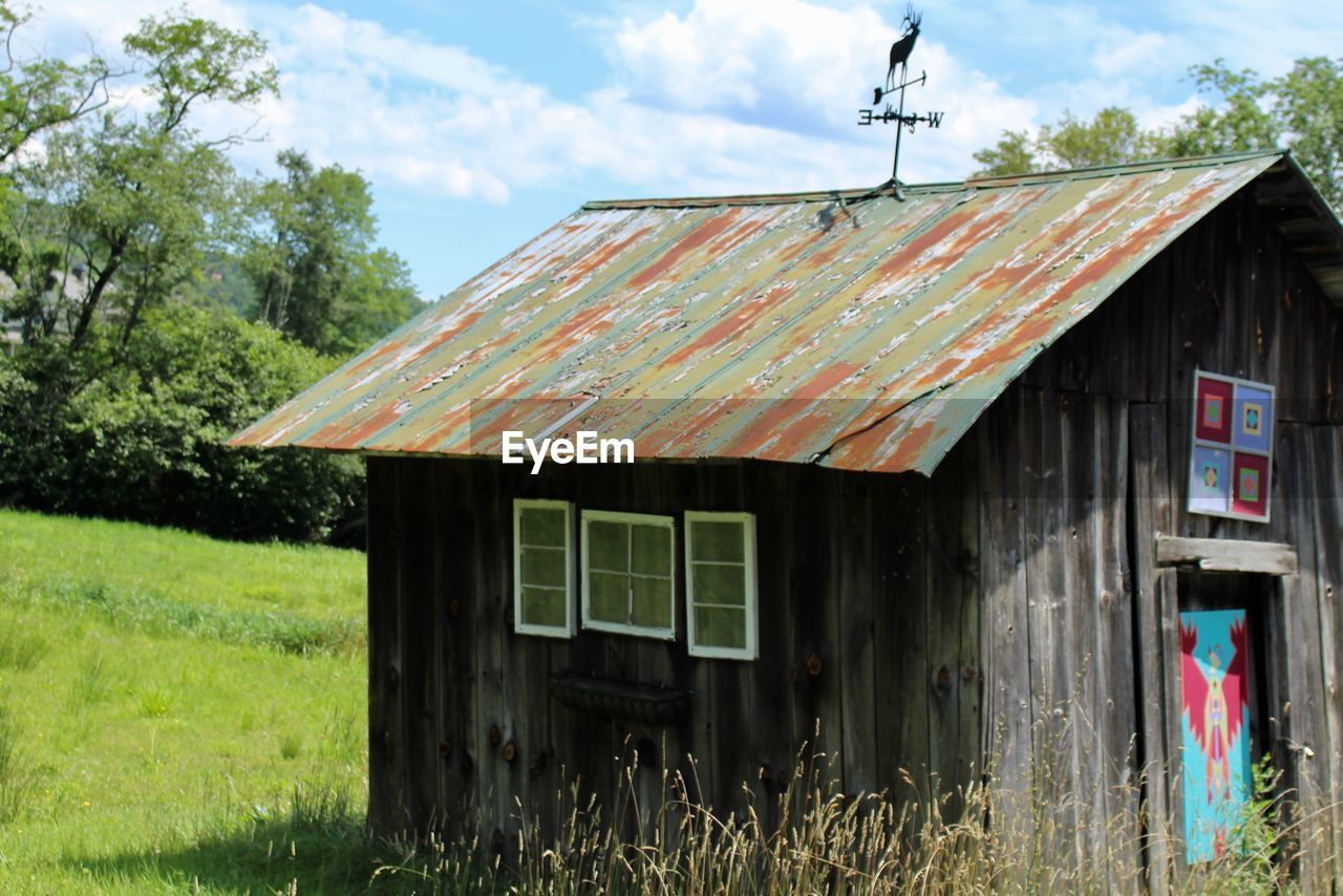 ABANDONED HOUSE ON FIELD BY TREES AGAINST SKY