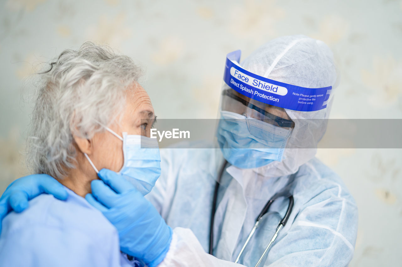 Doctor wearing protective suit examining patient in hospital