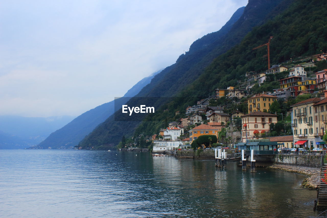 Town by lake and mountains against sky