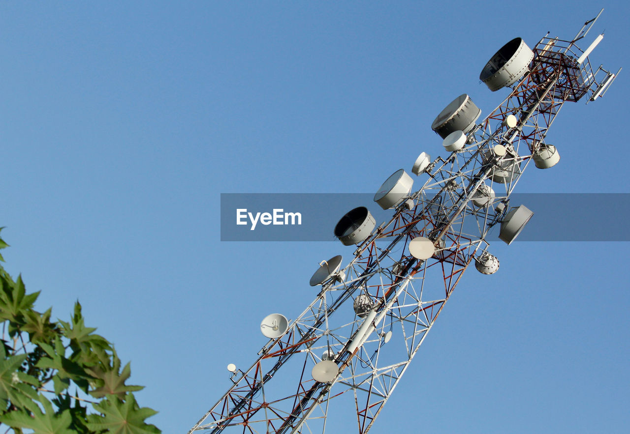 Low angle view of communications tower against clear blue sky