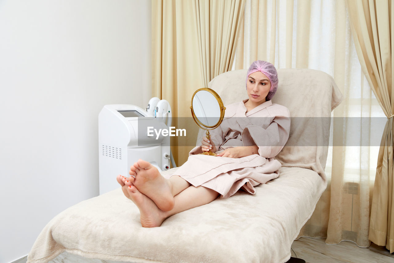 midsection of woman sitting on bed