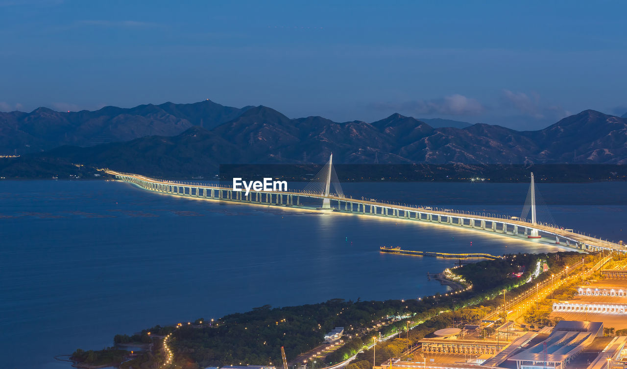 ILLUMINATED BRIDGE OVER BAY AGAINST SKY