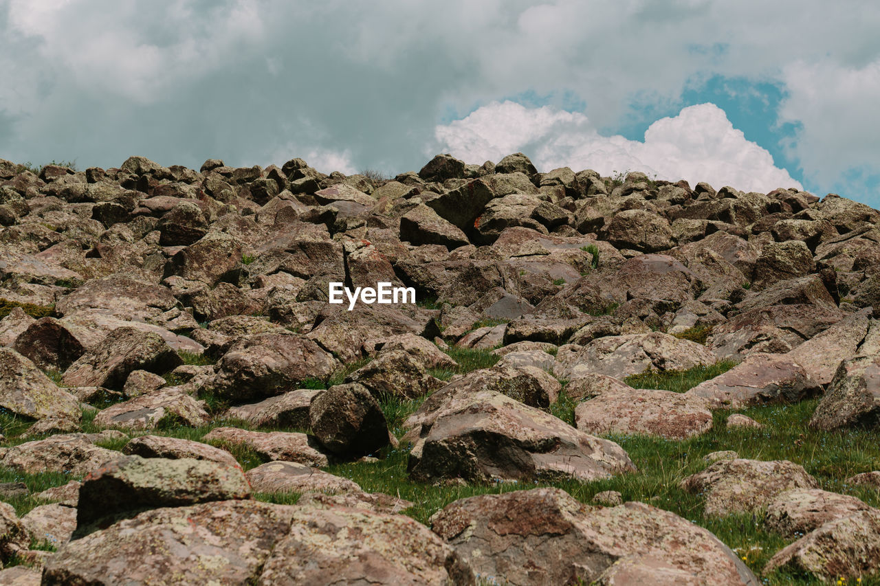 LOW ANGLE VIEW OF ROCKS ON MOUNTAIN AGAINST SKY