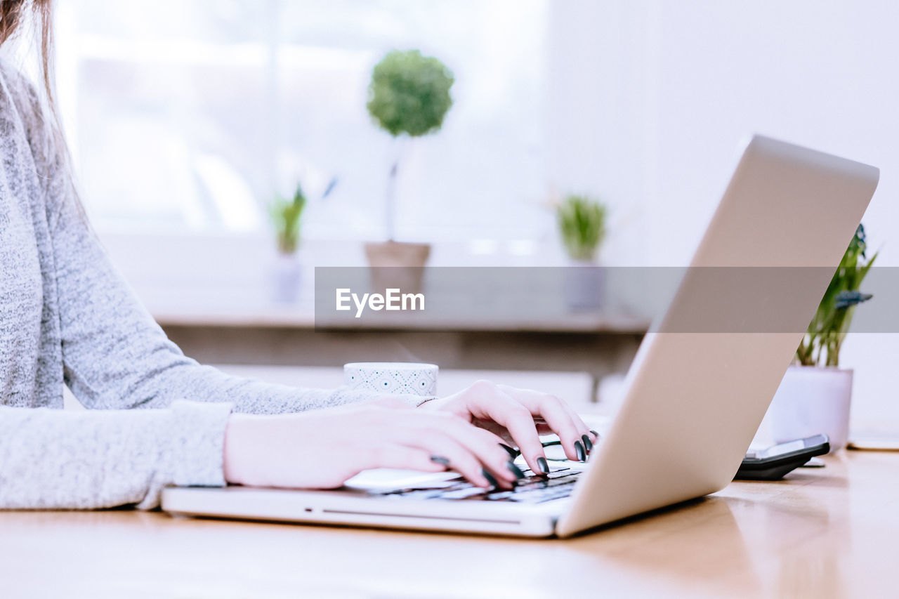 Woman using laptop on table at home