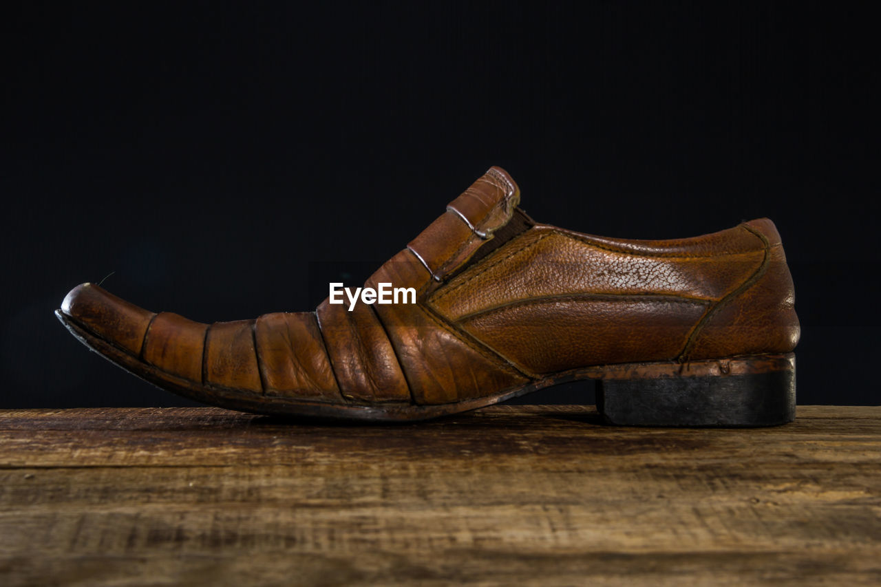 CLOSE-UP OF SHOES ON WOODEN TABLE