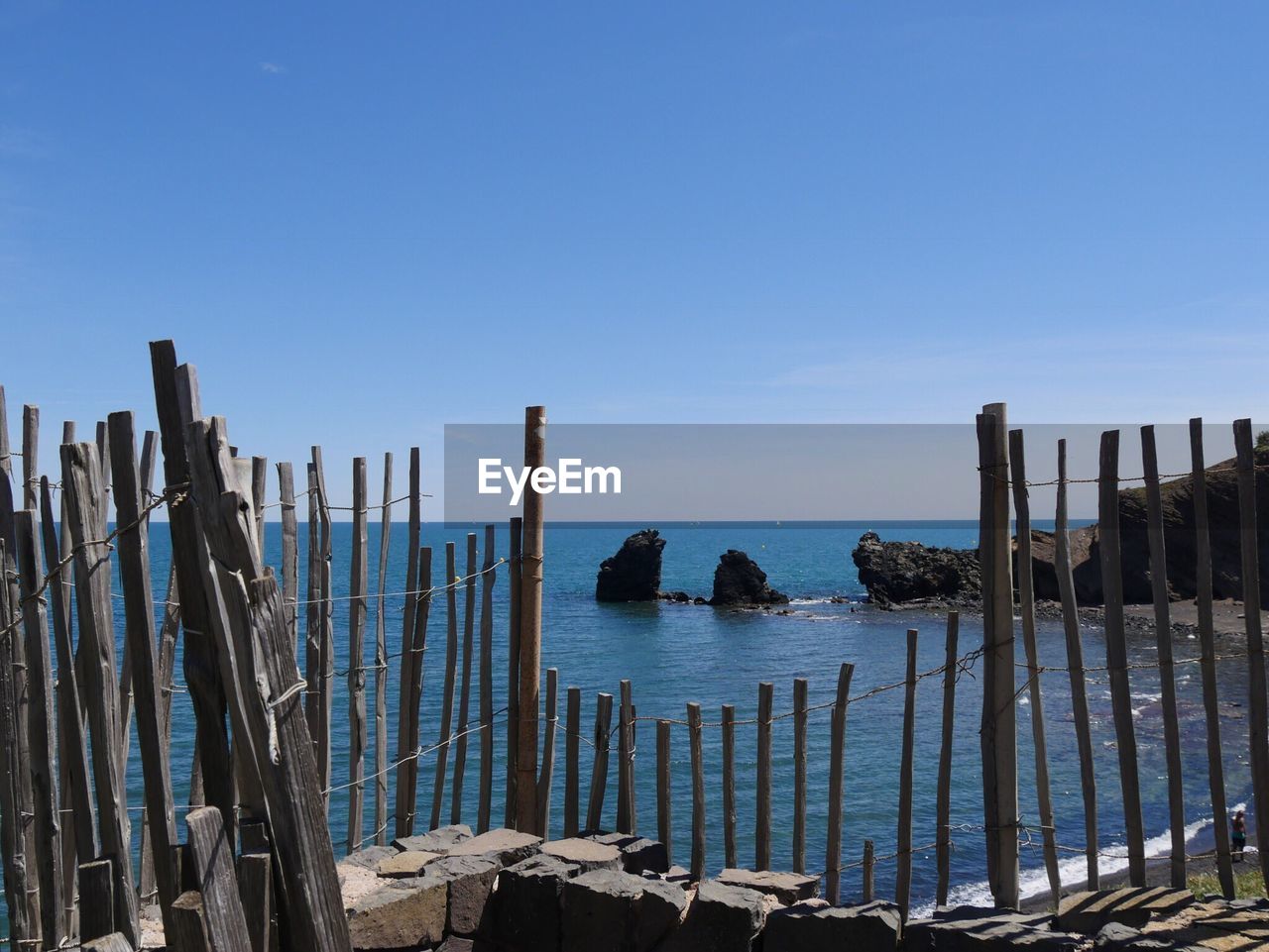 Wooden posts on beach against clear blue sky