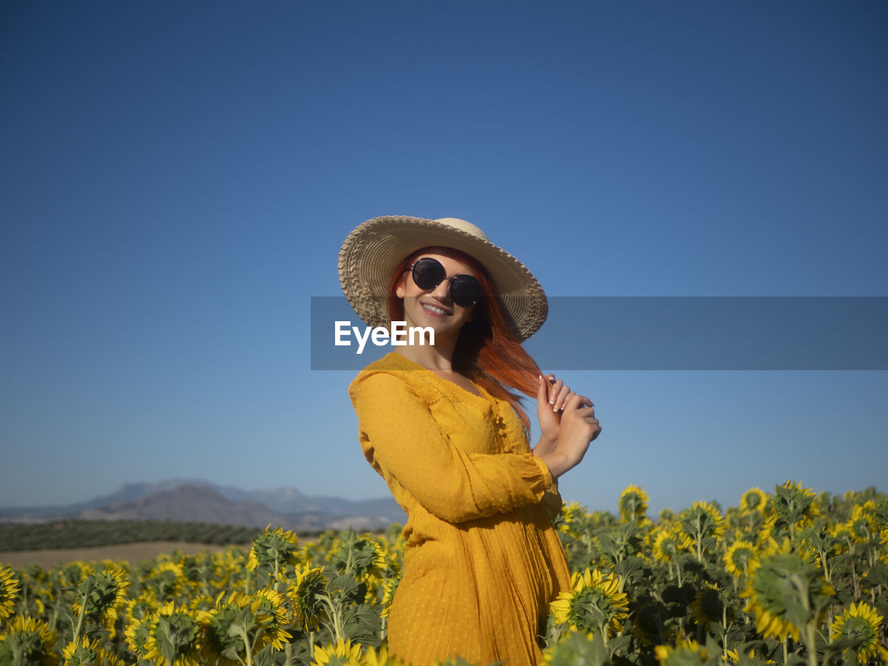 Portrait of young woman wearing hat standing against sky