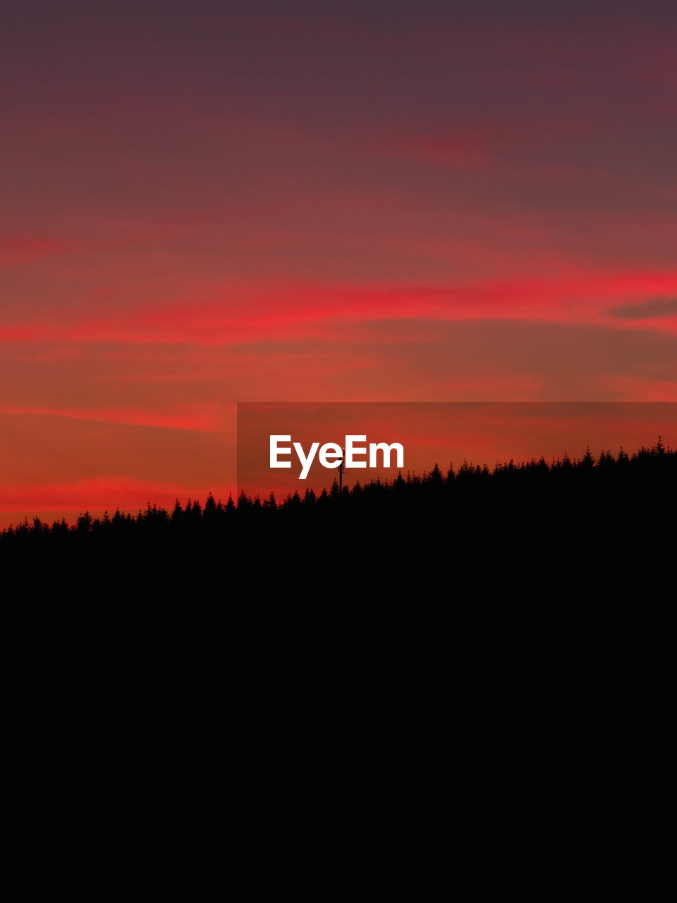Silhouette landscape against dramatic sky during sunset