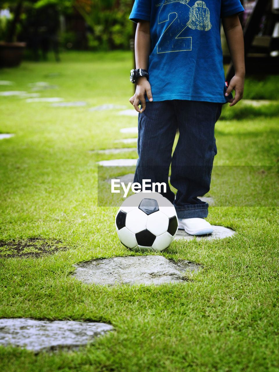 Low section of boy with soccer ball standing on field