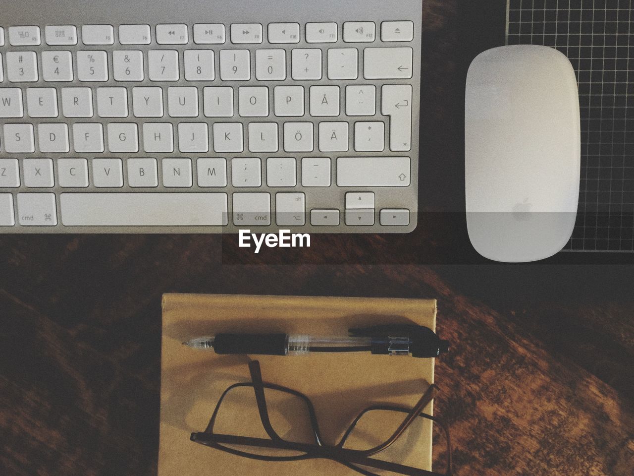 Directly above shot of keyboard and mouse by eyeglasses on table