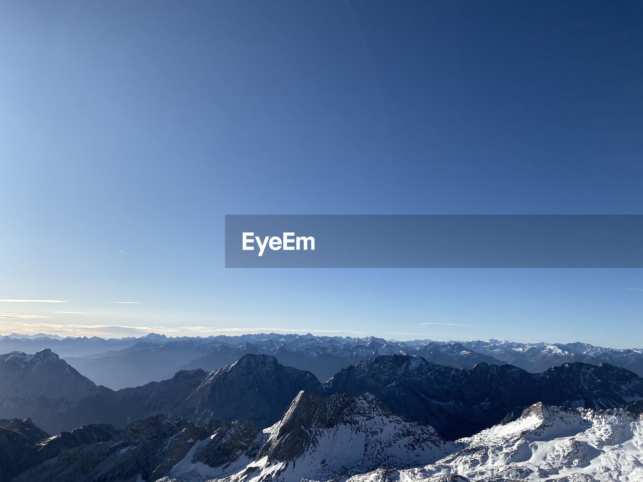 Scenic view of snowcapped mountains against blue sky