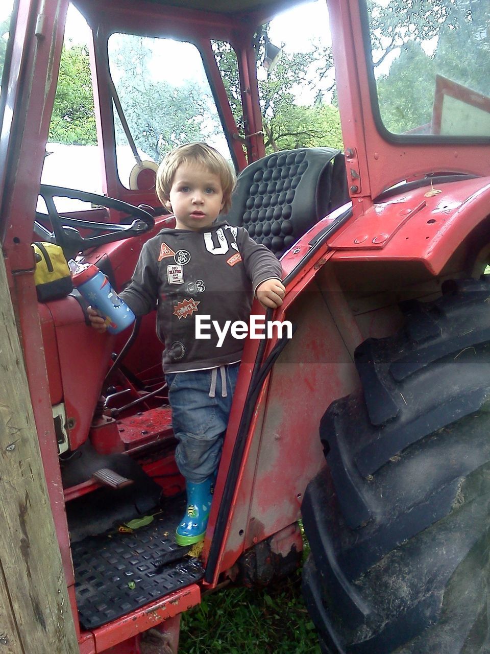 Full length portrait of boy standing in tractor