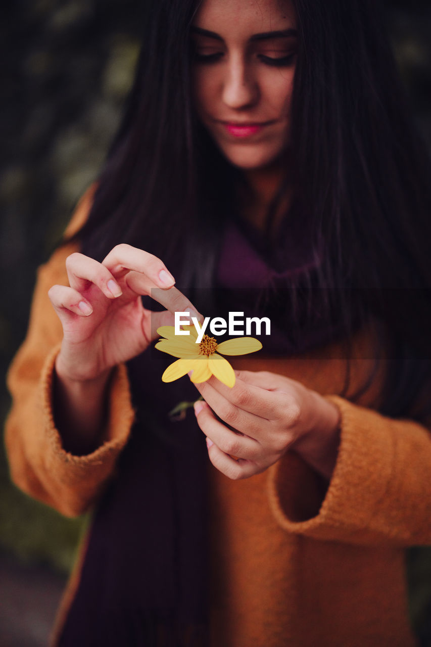 Young woman picks yellow flower petals in the field