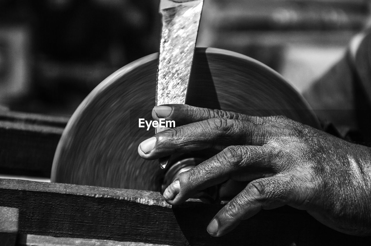 Cropped image of man sharpening knife at workshop