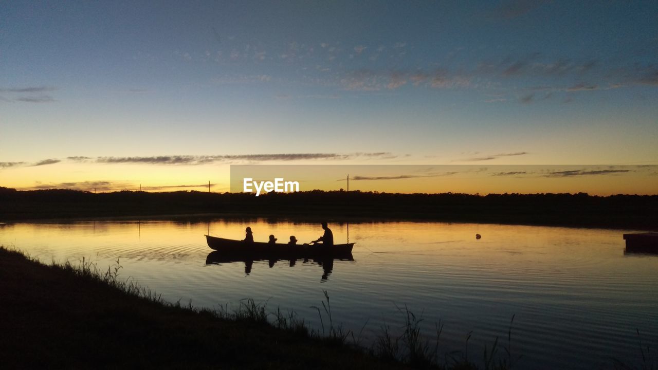 SILHOUETTE SHIP IN LAKE AGAINST SKY DURING SUNSET