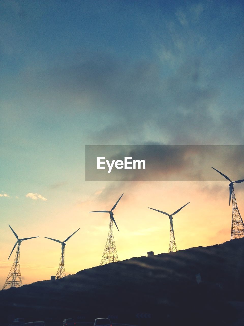 Low angle view of wind turbines against sky at dusk