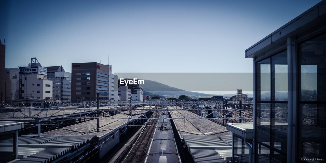 RAILROAD TRACKS AMIDST BUILDINGS AGAINST SKY