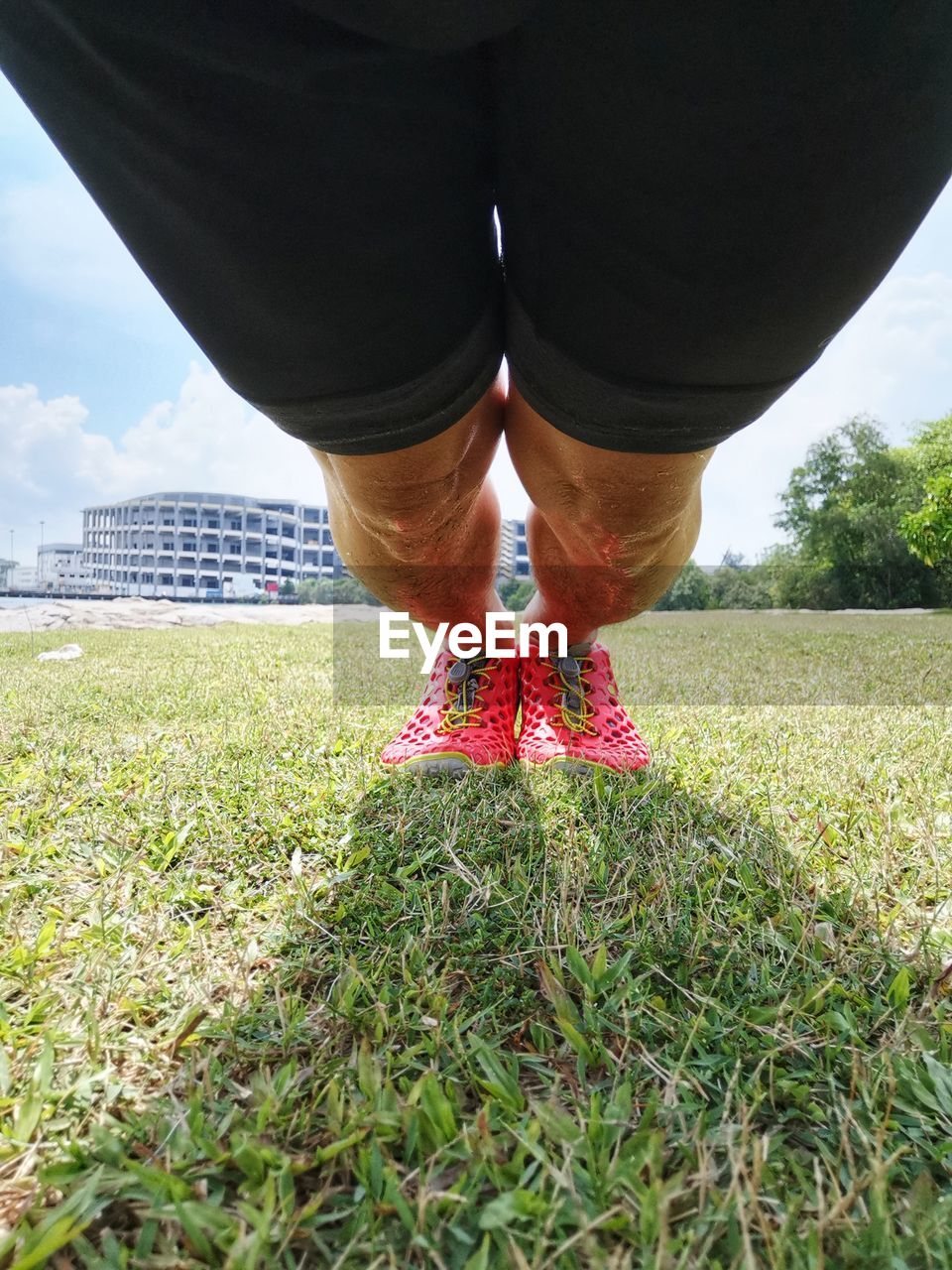 MIDSECTION OF WOMAN STANDING ON FIELD AGAINST SKY