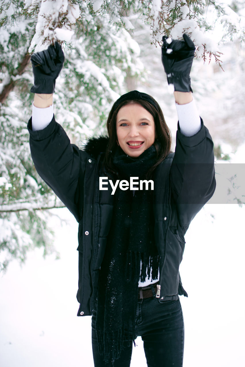 Portrait of smiling woman standing against snow