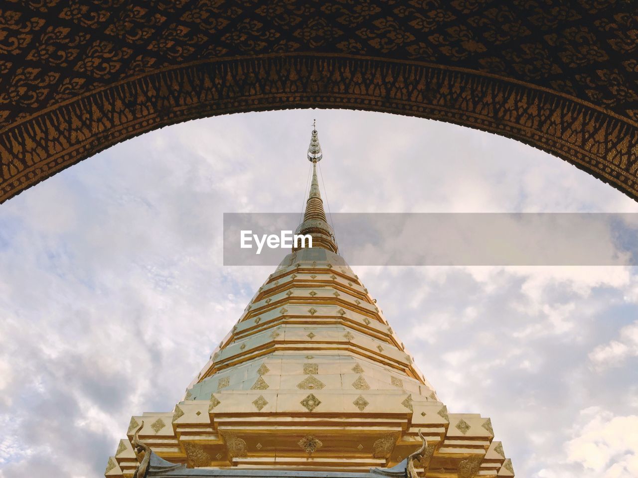 Low angle view of pagoda seen through arch against cloudy sky