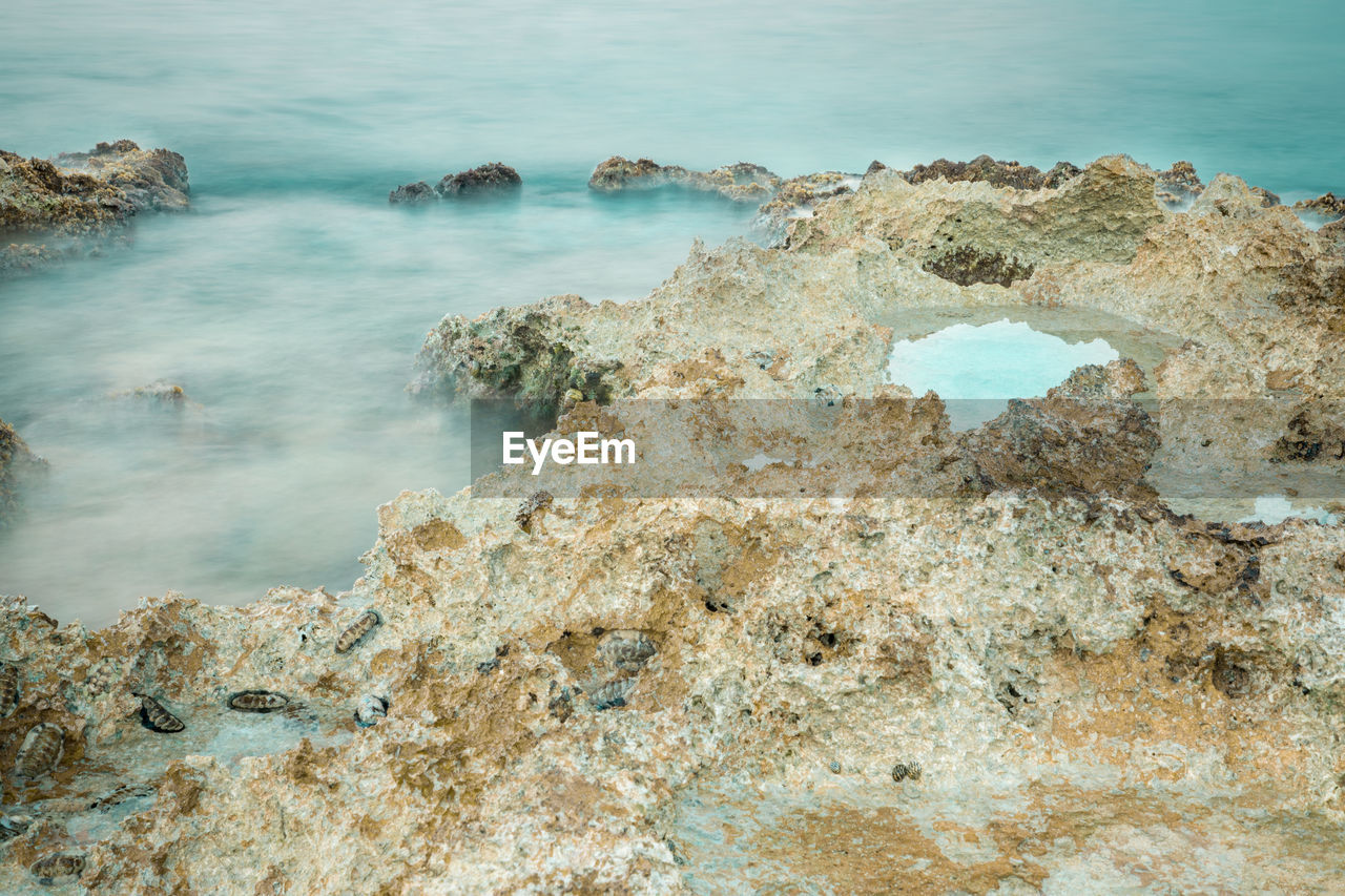 HIGH ANGLE VIEW OF ROCKS AT SEA SHORE