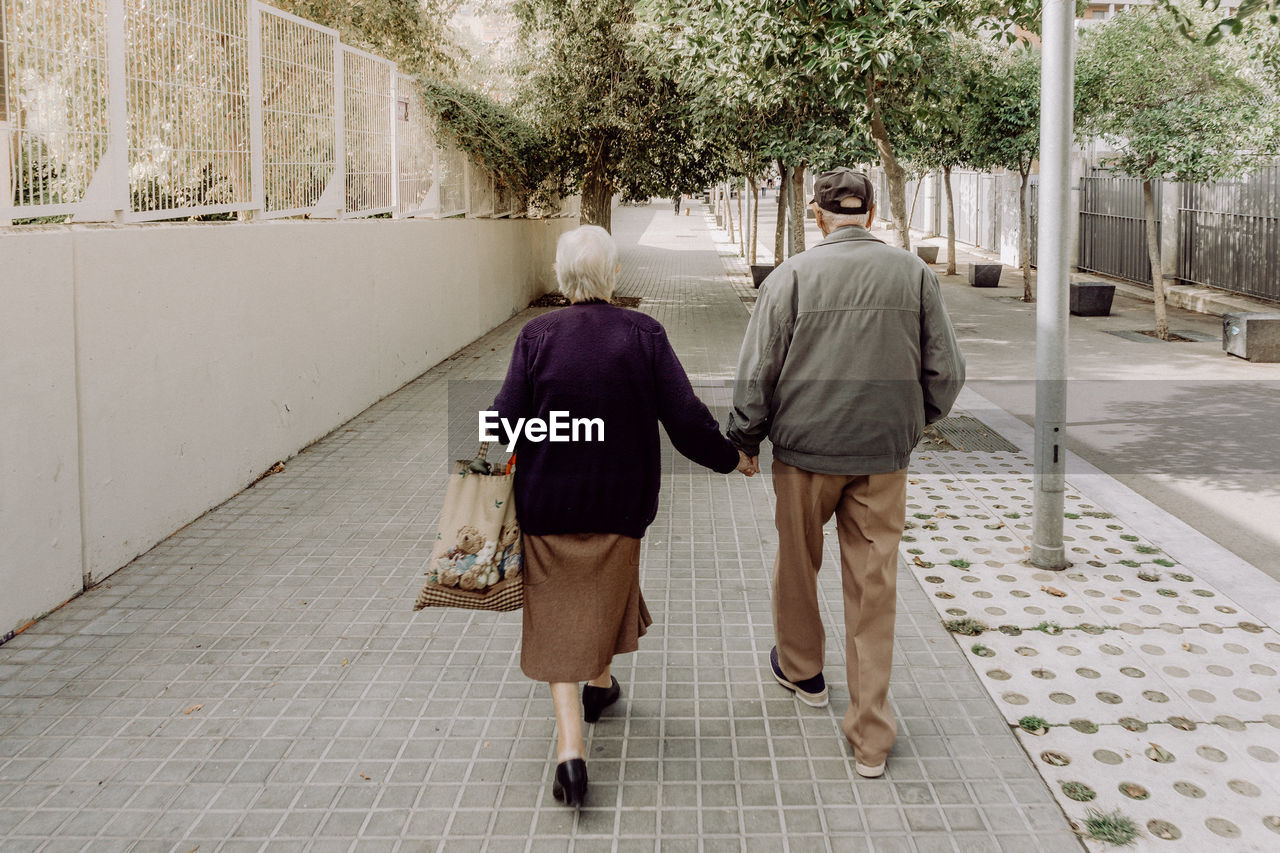 REAR VIEW OF TWO WOMEN WALKING ON FOOTPATH