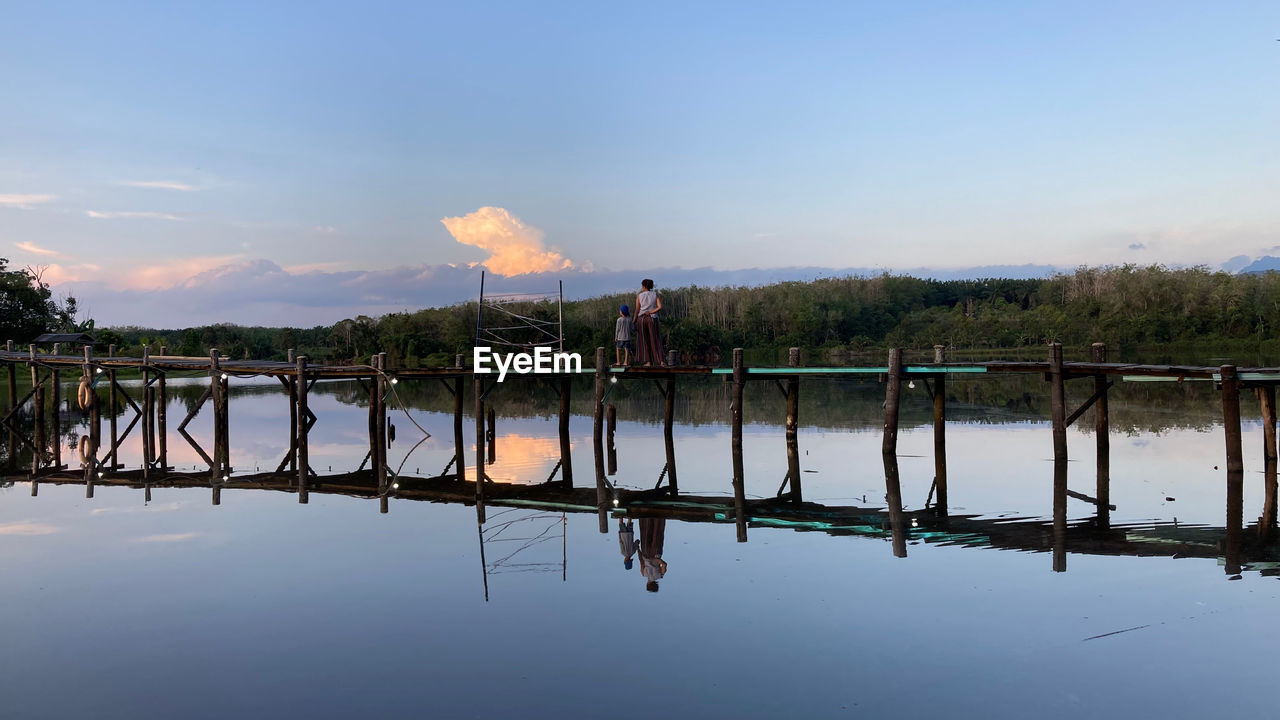 reflection, water, sky, morning, nature, river, cloud, shore, dusk, dock, tranquility, beauty in nature, reservoir, tree, environment, landscape, outdoors, scenics - nature, body of water, architecture, men, blue, plant, horizon, waterway, travel, tranquil scene, travel destinations, day, transportation