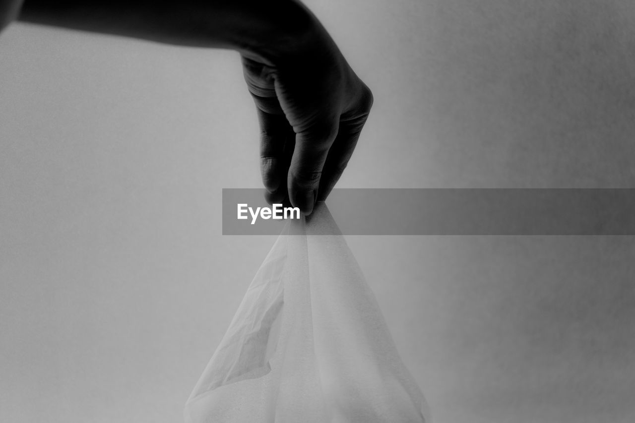 Cropped image of person holding napkin against wall