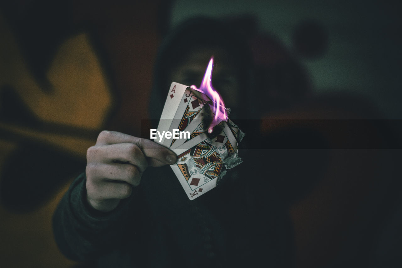 Close-up of person holding burning cards