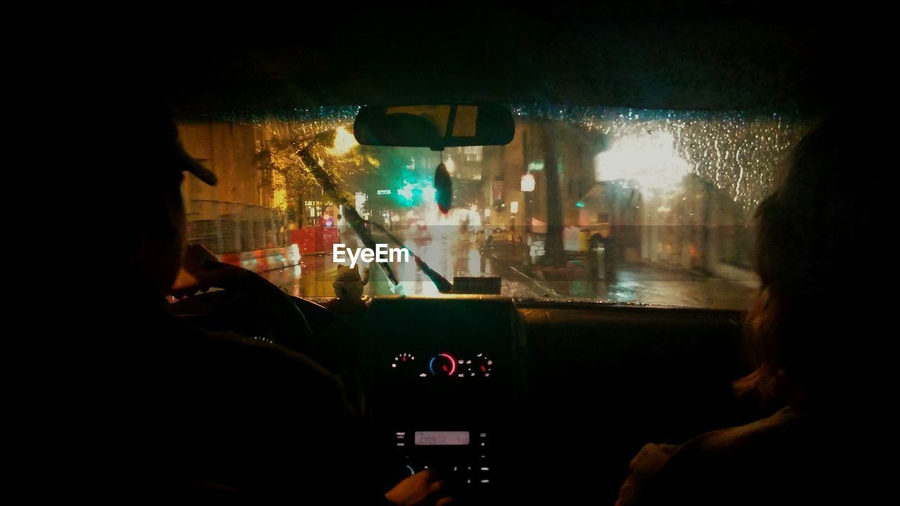 Rear view of people traveling in car at night during monsoon