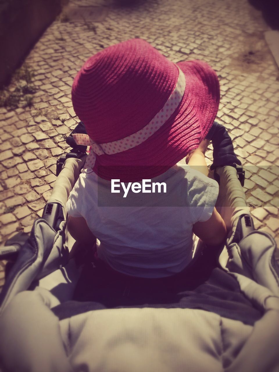 High angle view of girl with pink hat sitting in baby stroller