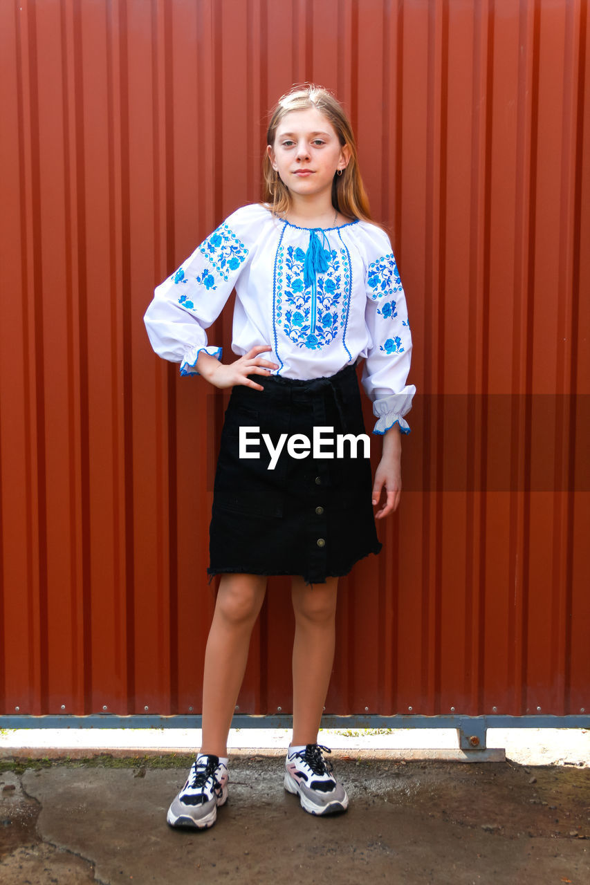 Ukraine child. ukrainian teen girl in vyshyvanka standing outside in skirt and sneakers. pray 