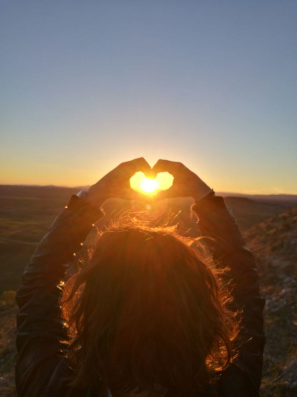 REAR VIEW OF WOMAN IN SUNSET