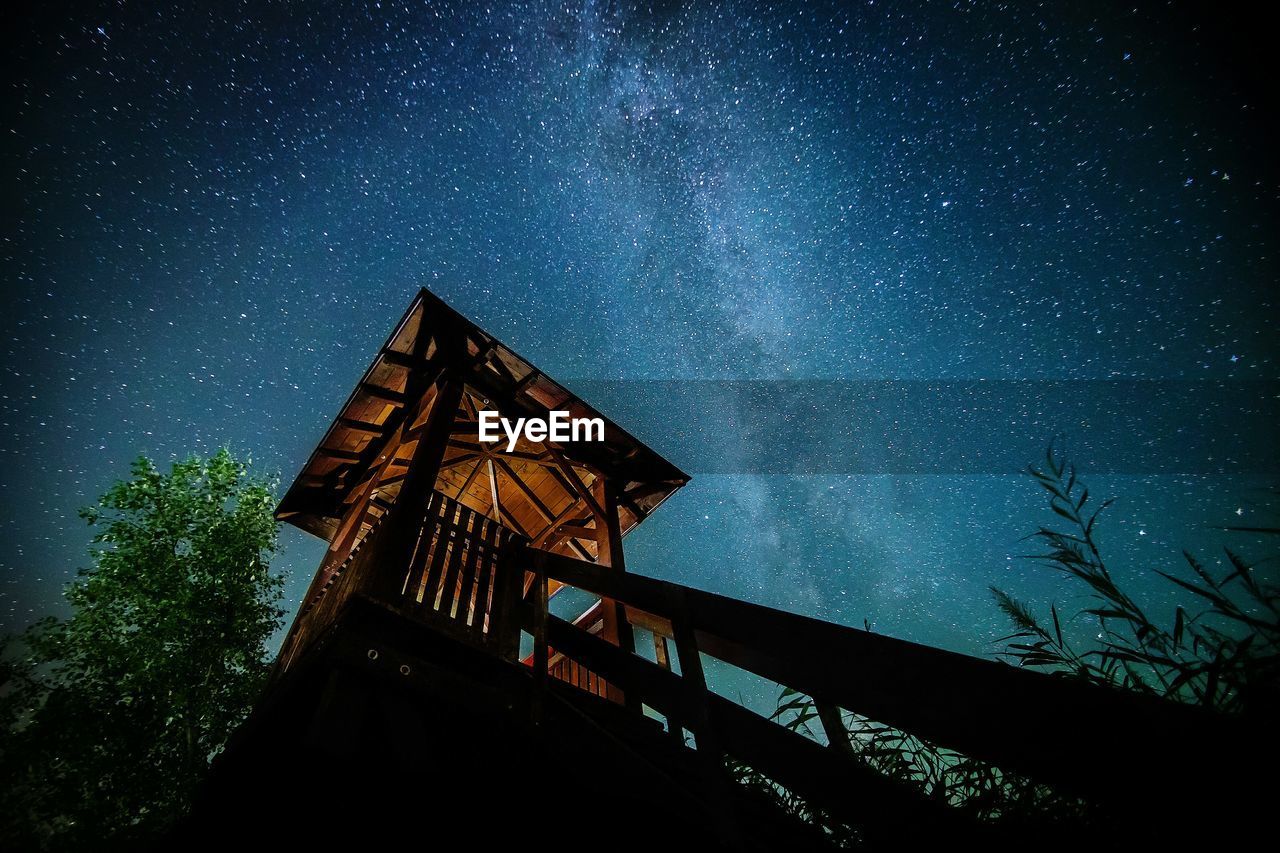 Low angle view of lookout tower against star field at night