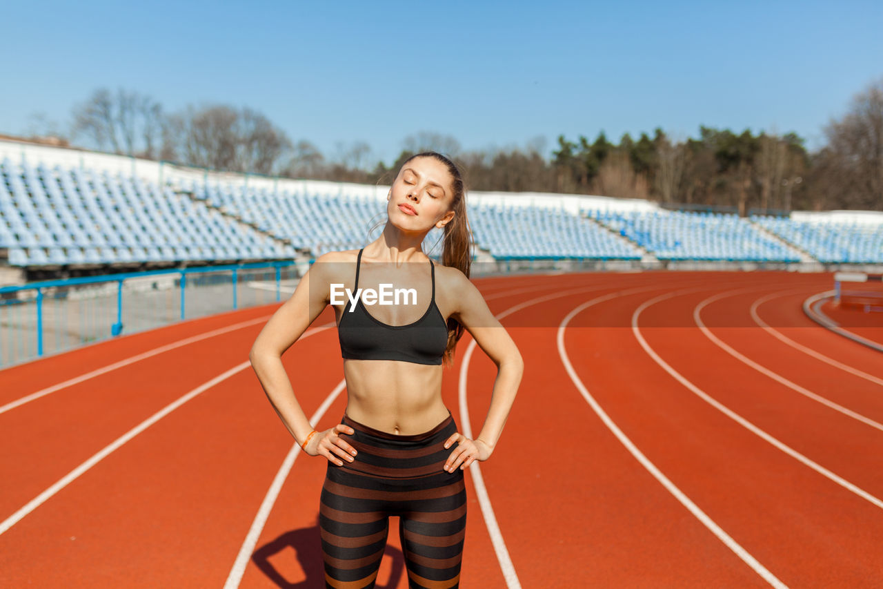 Woman standing with arms akimbo on stadium