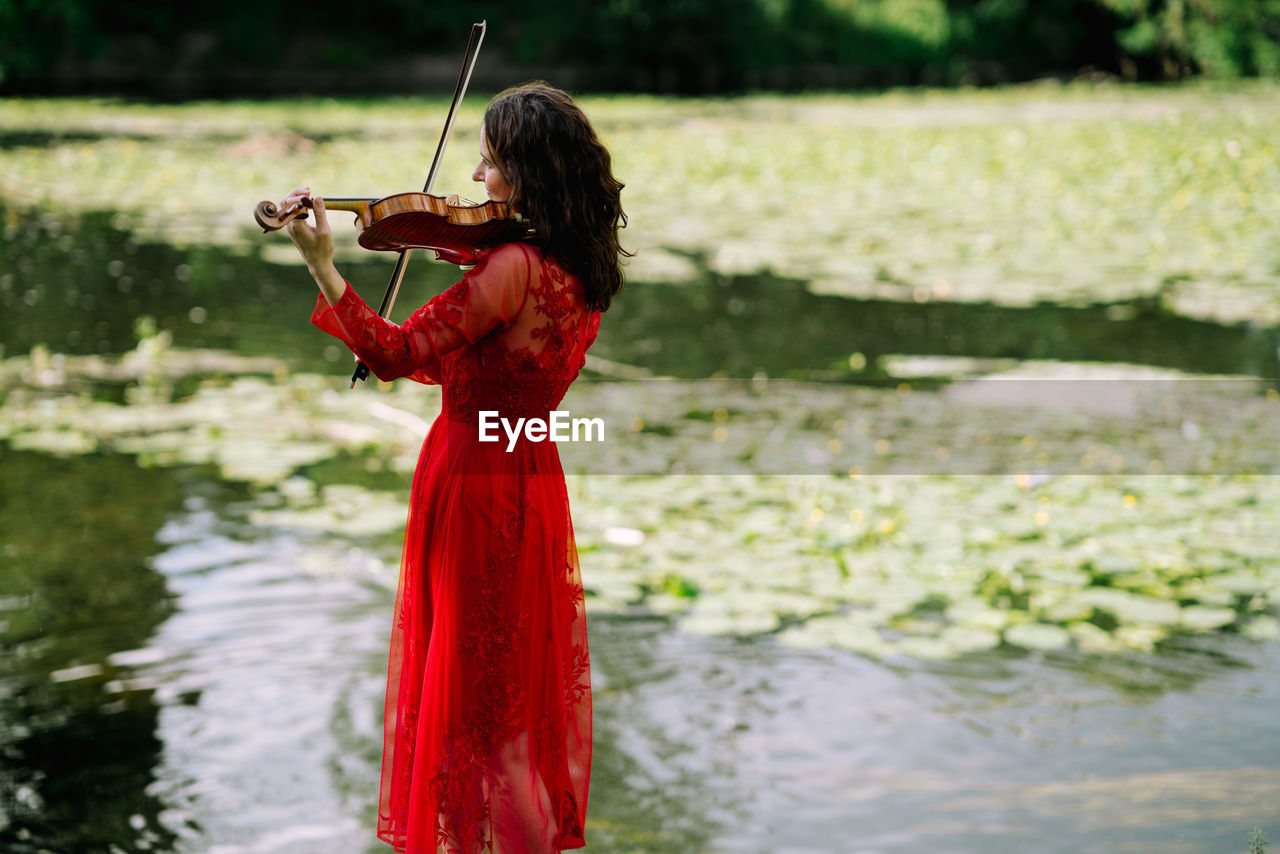 WOMAN HOLDING RED WHILE STANDING IN LAKE