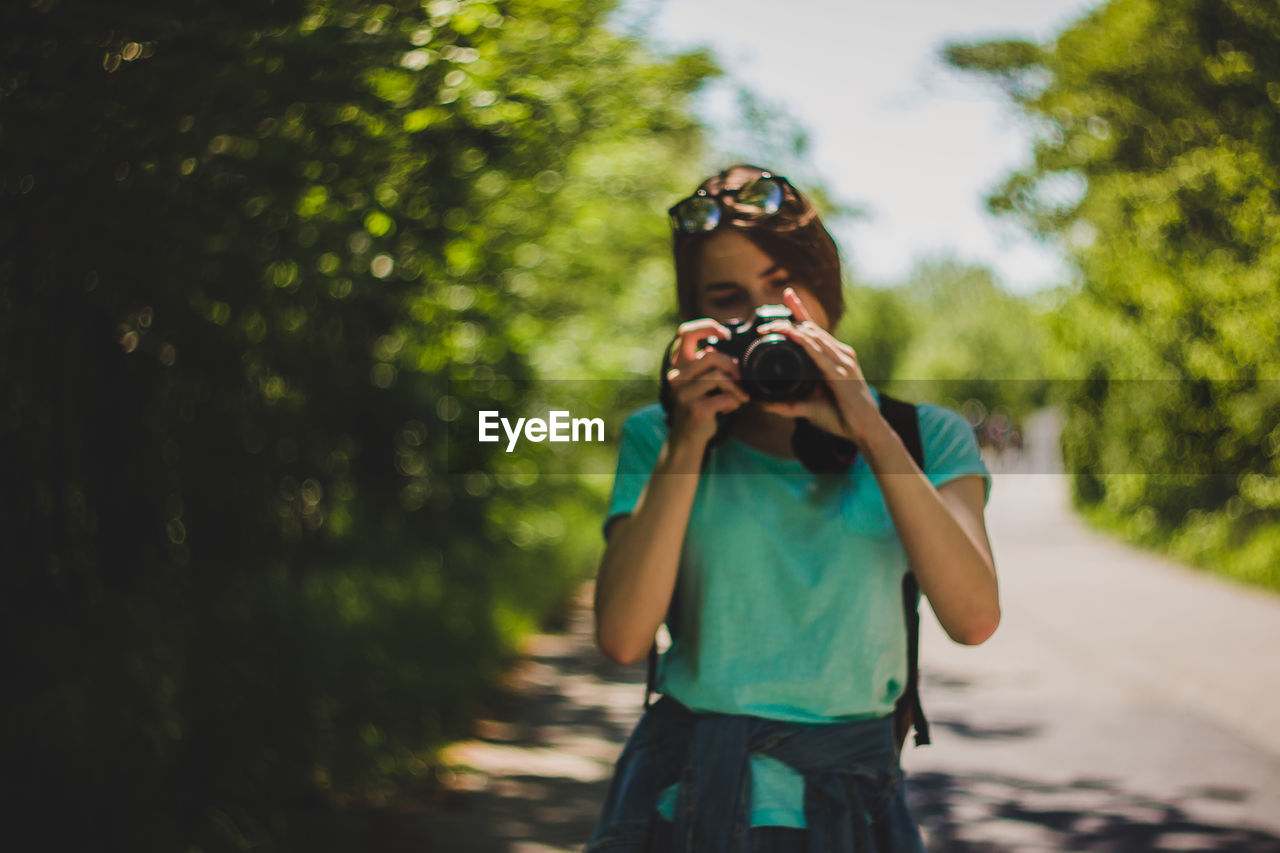 Young woman photographing on road