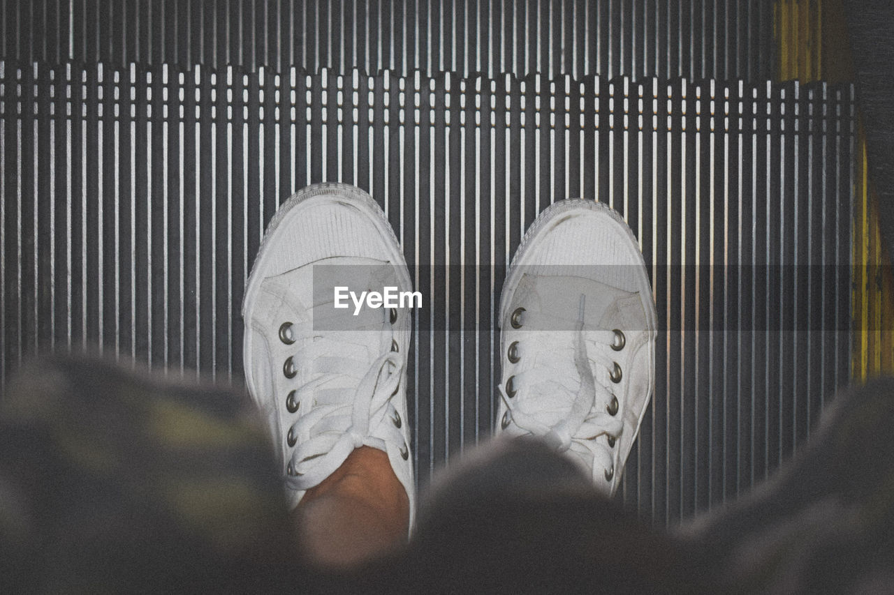 Low section of man standing on escalator