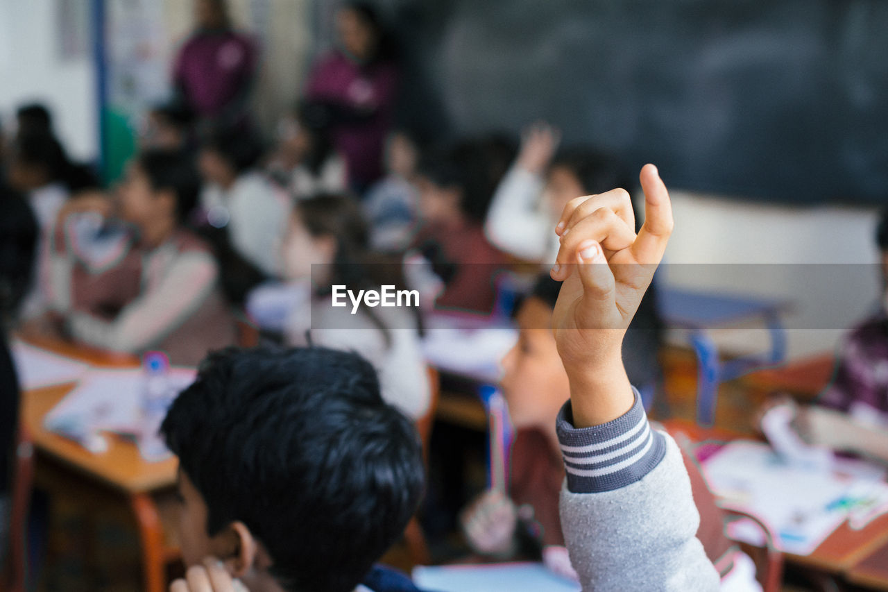 Close-up of hand raised in classroom