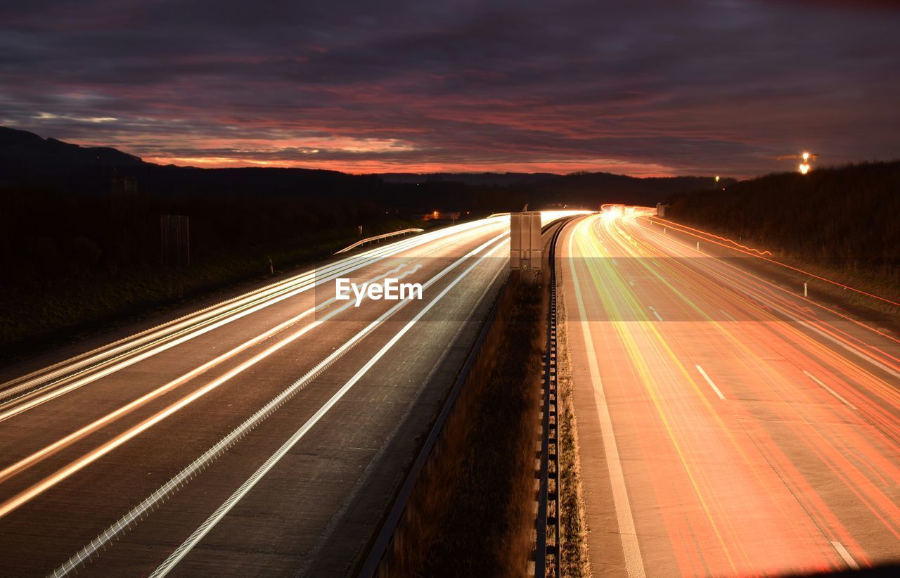 LIGHT TRAILS ON ROAD AGAINST SKY AT NIGHT