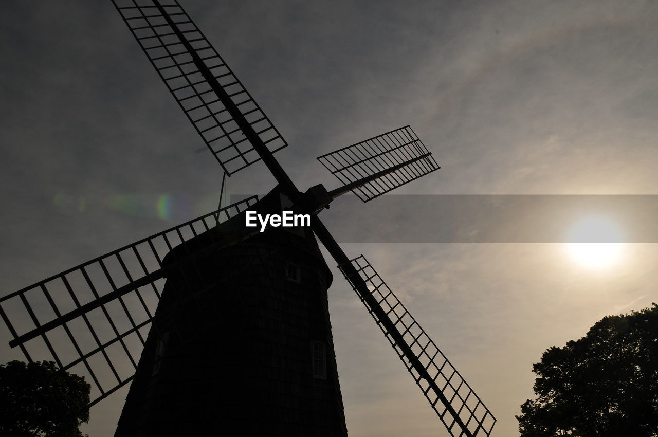 Low angle view of traditional wooden windmill against sky at sunrise