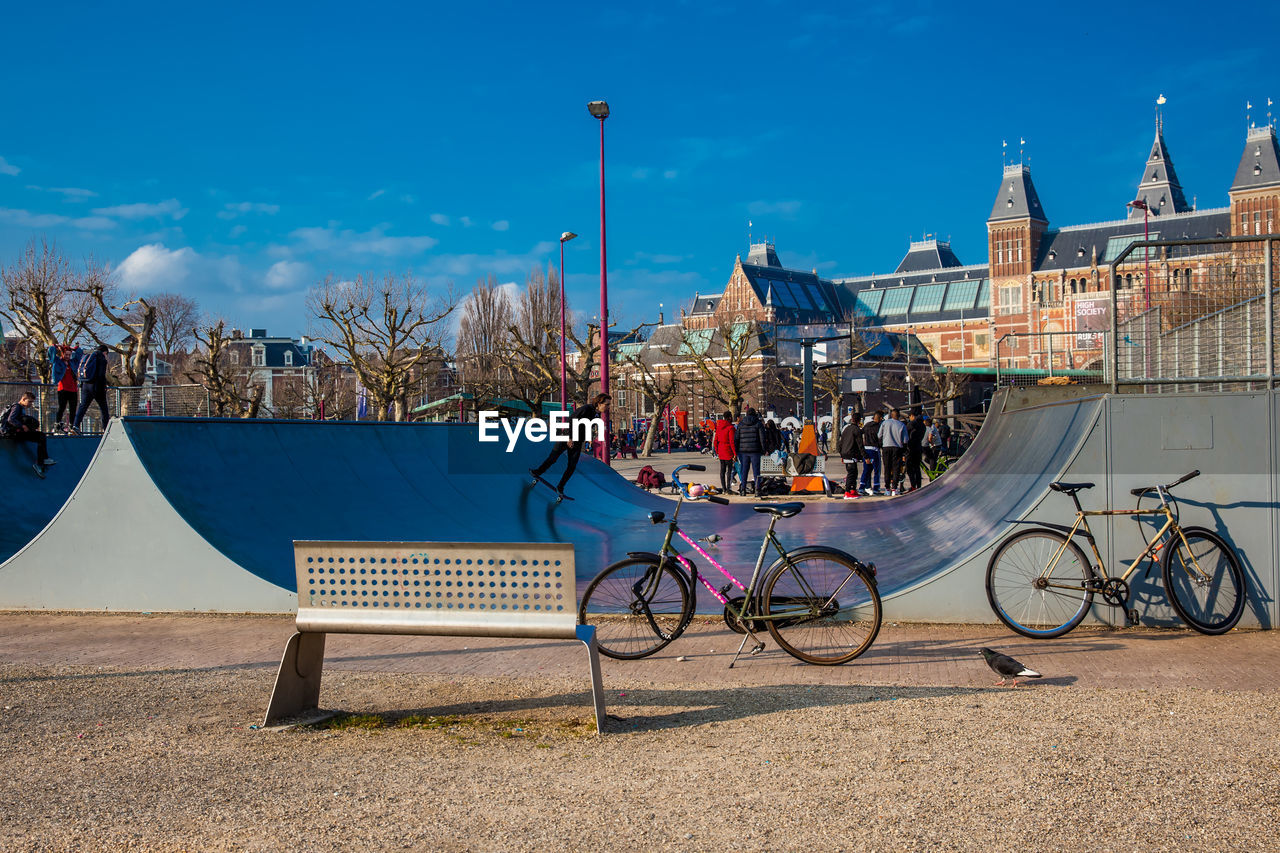 BICYCLES ON STREET BY BUILDINGS AGAINST SKY