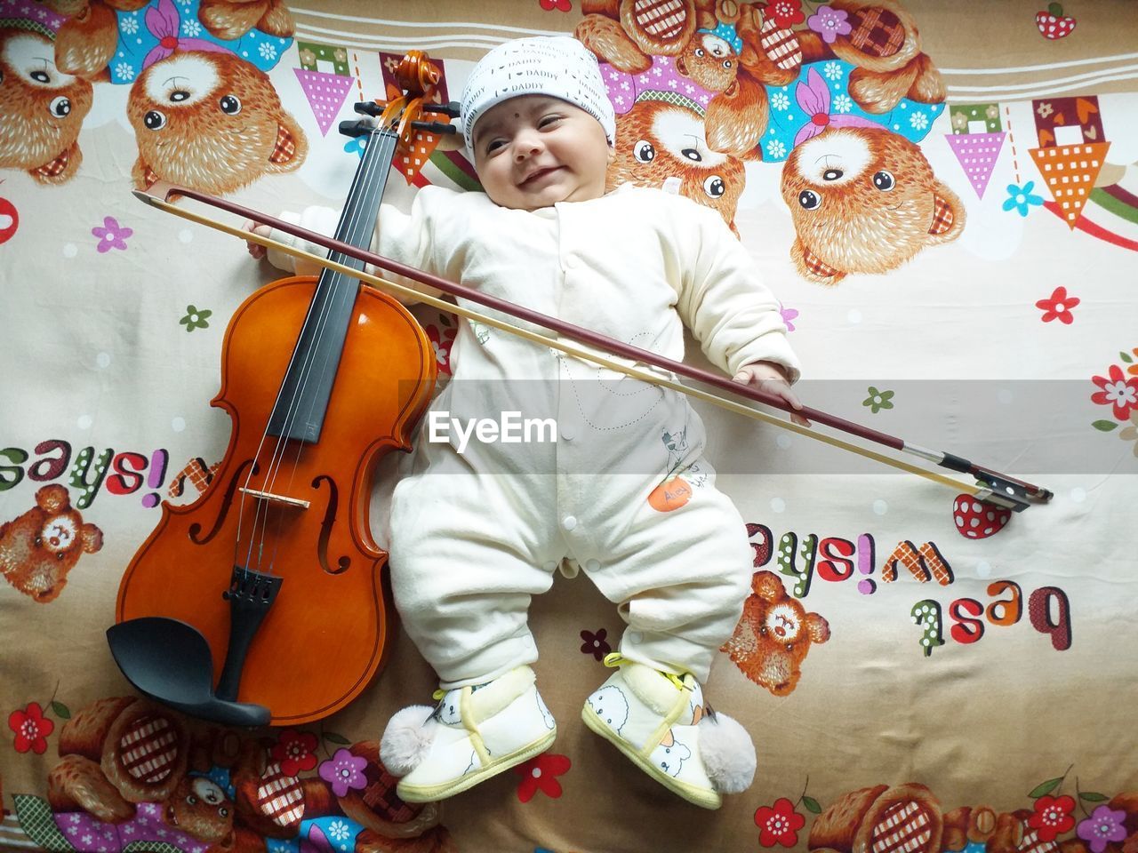 Full length of cute baby with violin on bed at home