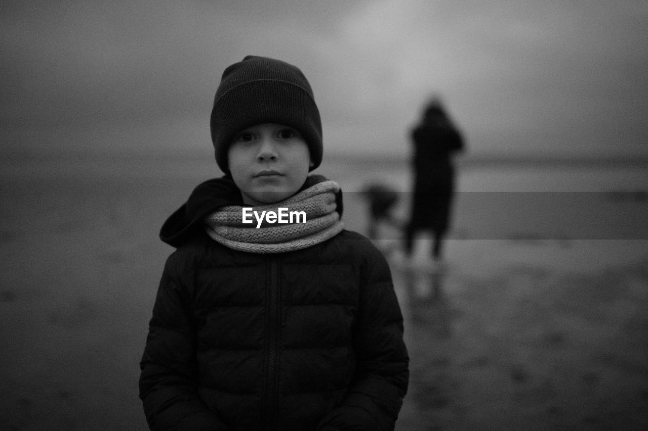 Portrait of boy standing at beach during winter